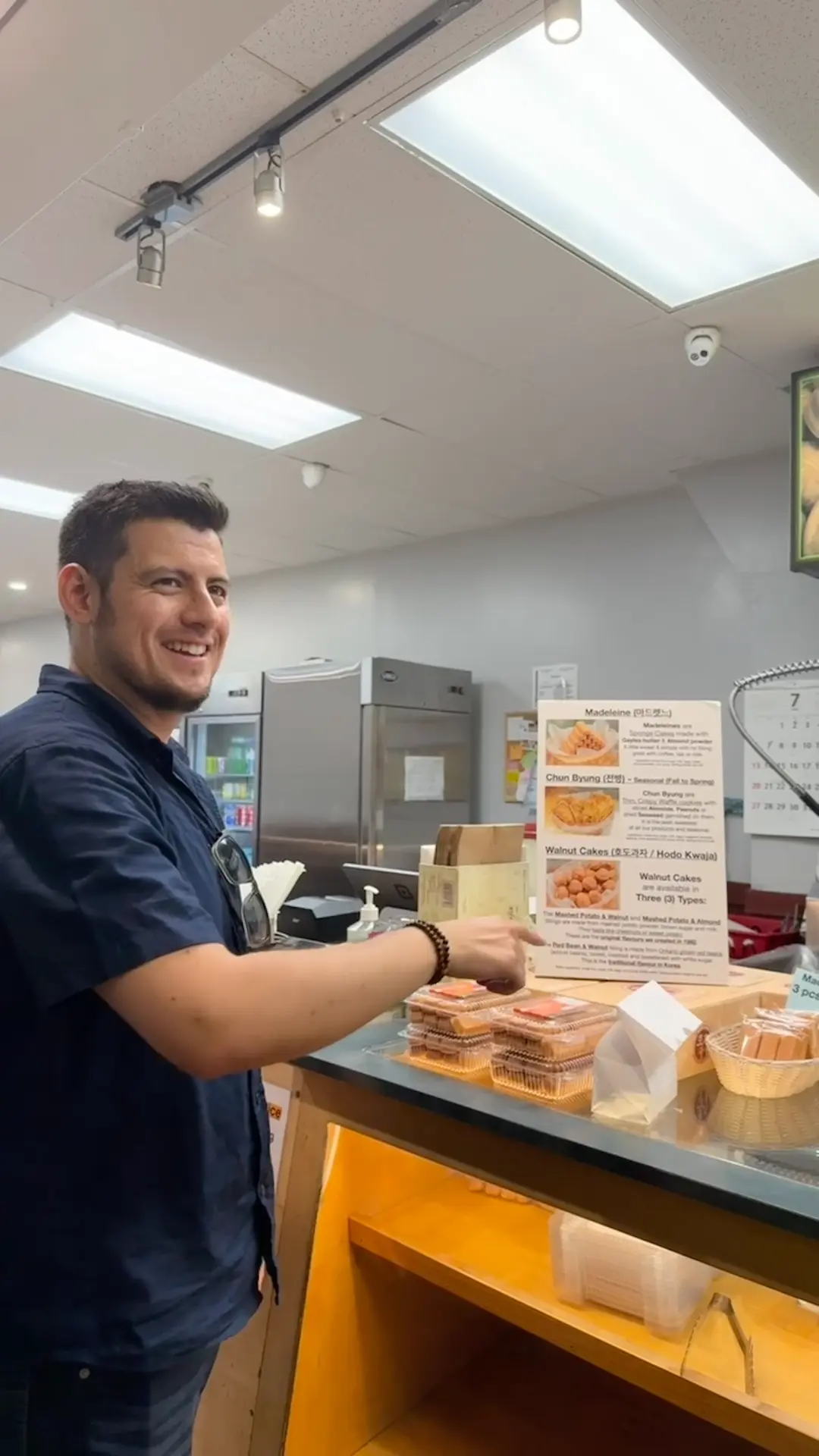 Mike pointing out Korean walnut cakes and madeleines at a Koreatown bakery counter